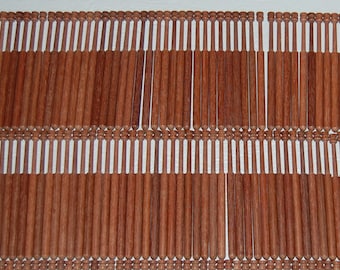 May include: A set of 60 wooden bobbins for lace making. The bobbins are arranged in rows on a white surface. The bobbins are a light brown color and have a smooth finish.
