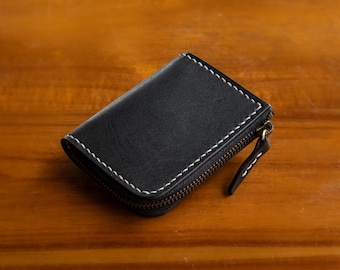 May include: A black leather zippered wallet with white stitching.
