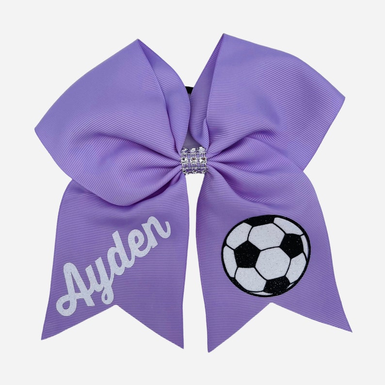 May include: Purple cheer bow with a white soccer ball and the name "Ayden" in white script.