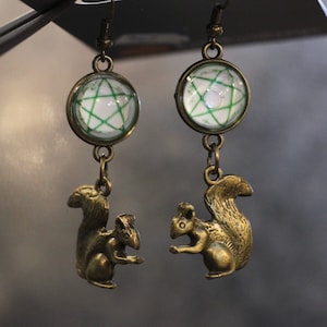 May include: A pair of bronze earrings featuring a squirrel charm and a glass pendant with a green star design.