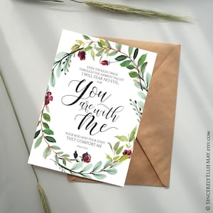 K&ouml;nnte beinhalten: Eine Gru&szlig;karte mit dem Text "You are with Me" in eleganter Schrift, umgeben von einem Aquarell-Blumenkranz aus gr&uuml;nen Bl&auml;ttern und burgunderfarbenen Bl&uuml;ten. Die Karte wird mit einem braunen Umschlag pr&auml;sentiert.
