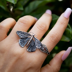 Può includere: Un anello d'argento con un design a farfalla dettagliato e una fascia di pietre di marcasite.