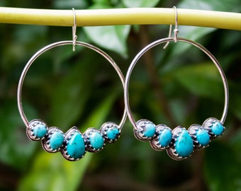 May include: Silver hoop earrings with a row of five turquoise stones set in silver.