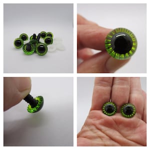 May include: A close-up of green plastic safety eyes with black pupils. The eyes have a textured, ring-like design around the pupil. The eyes are on a white background.