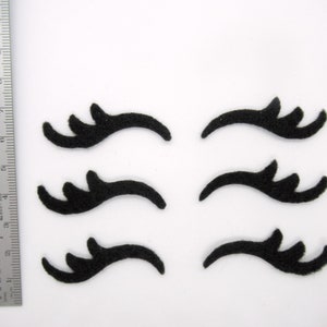 May include: Six black felt eyelashes, each with a unique shape and curve, ideal for crafting or decorating.