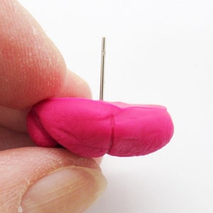 May include: A bright pink polymer clay earring with a silver post.