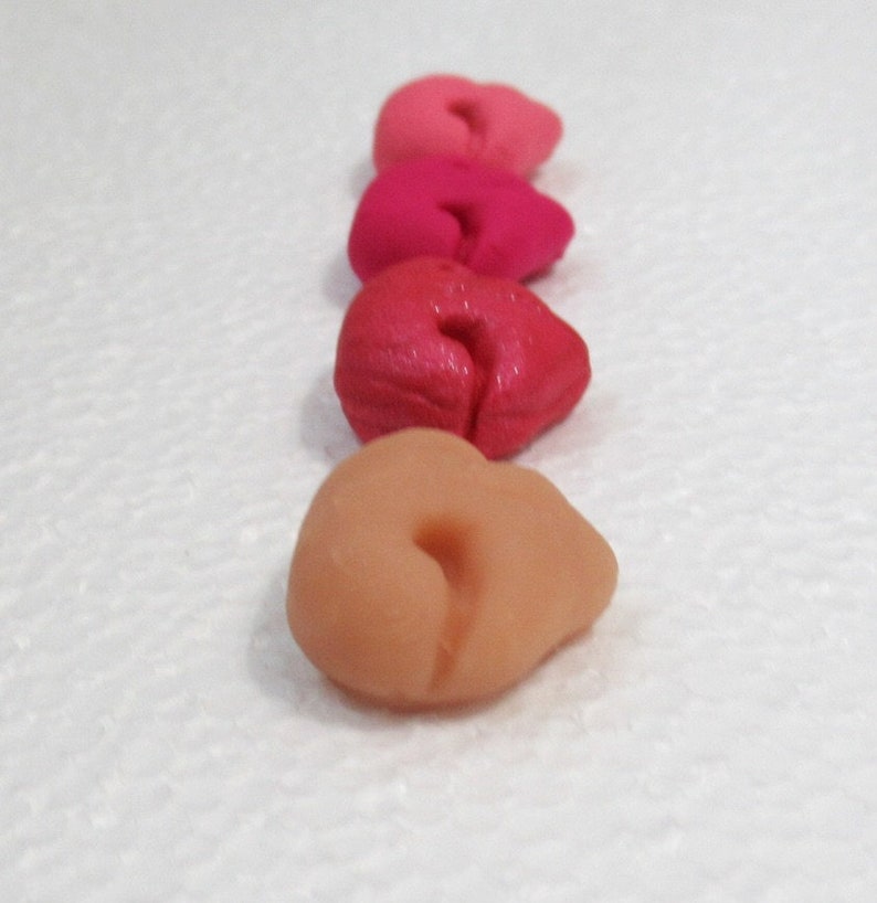 May include: Four heart-shaped clay pieces in shades of pink, red, and orange. The pieces are arranged in a row from lightest to darkest.