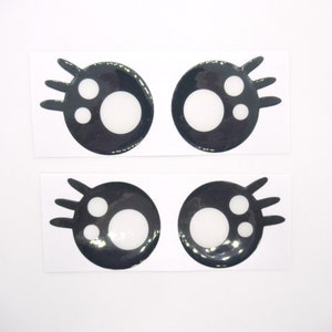 May include: Four black and white googly eyes with eyelashes. Each eye has a white pupil and a smaller white dot.