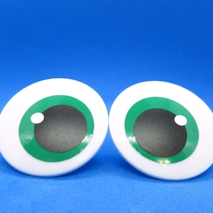 May include: Two large, cartoon-style eye decorations. Each eye has a white iris, a green iris ring, a black pupil, and a small white highlight. The eyes are set against a bright blue background.