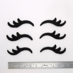 May include: Six black felt eyelashes, each with a unique shape and design, ideal for crafting projects or adding a whimsical touch to decorations.