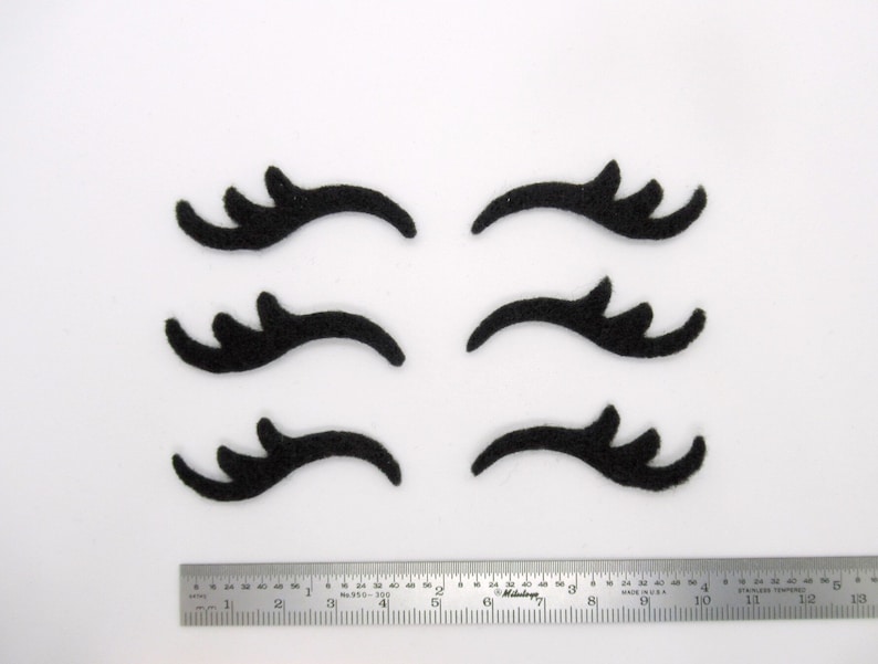 May include: Six black felt eyelashes, each with a unique shape and design, ideal for crafting projects or adding a whimsical touch to decorations.