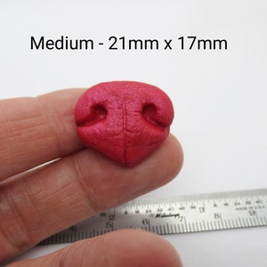 May include: A medium-sized, pink, faux leather, dog nose for crafting. The nose measures 21mm x 17mm.