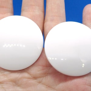 May include: Two white round buttons with a glossy finish.