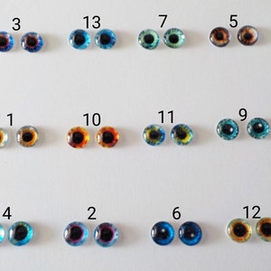 May include: Twelve pairs of glass eyes for doll making, numbered 1 through 13. The eyes are various colours, including blue, green, brown, and yellow.