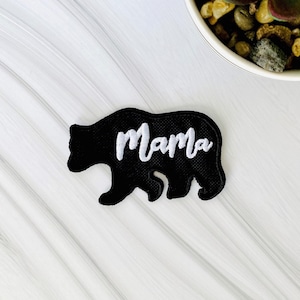 May include: Black felt iron-on patch with a black bear silhouette and the word "Mama" embroidered in white.