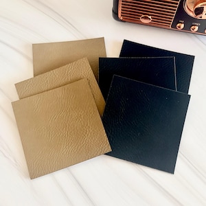 May include: A collection of square coasters with a textured surface, featuring three in a light tan color and three in a deep black color, arranged in a overlapping stack next to a black and rose gold vintage-style radio with a circular dial.