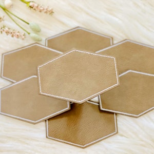 Pode incluir: Conjunto de seis  tapetes de couro marrom hexagonais com costuras brancas. Os tapetes est&atilde;o empilhados uns sobre os outros.