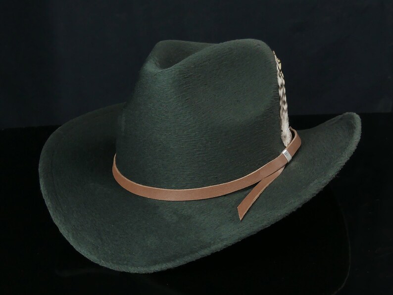 May include: A dark green felt cowboy hat with a brown leather band and a feather accent.