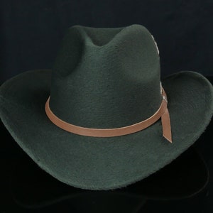 May include: A dark green felt cowboy hat with a brown leather band and a brown leather strap.