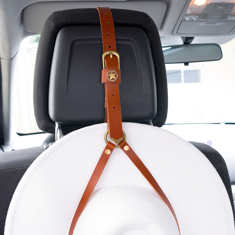 Brown leather Western-star car headrest cowboy hat holder holding a white hat