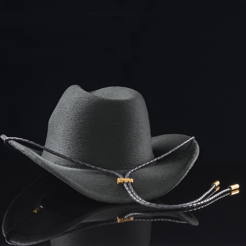 Black four-strand braided leather cowboy hat strap with gold hardware, photographed with a dark cowboy hat