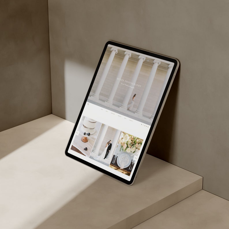 Może przedstawiać: Tablet wyświetlający stronę internetową firmy fotograficznej specjalizującej się w fotografii ślubnej, o nazwie "Millie Photography". Strona zawiera zdjęcia pary ślubnej, tortu weselnego i kompozycji kwiatowych.