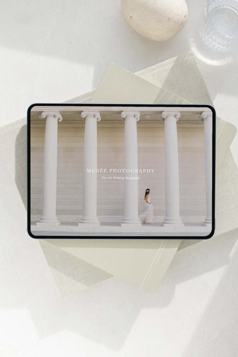 Może przedstawiać: Tablet cyfrowy wyświetlający zdjęcie panny młodej w białej sukni idącej między białymi kolumnami. Na tablecie widnieje tekst "MUS&Eacute;E PHOTOGRAPHY Fine Art Wedding Photography".