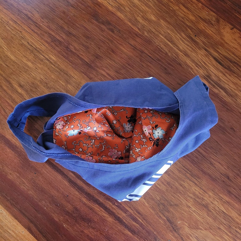 Navy blue bag from above on wooden surface. Bag is scrunched down and open to show orange floral lining inside.