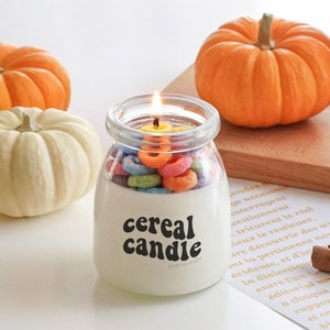 a lit fruit loops cereal candle filled with colorful cereal wax melts, cinnamon sticks, white and orange pumpkins, Ikea mini wood cutting board