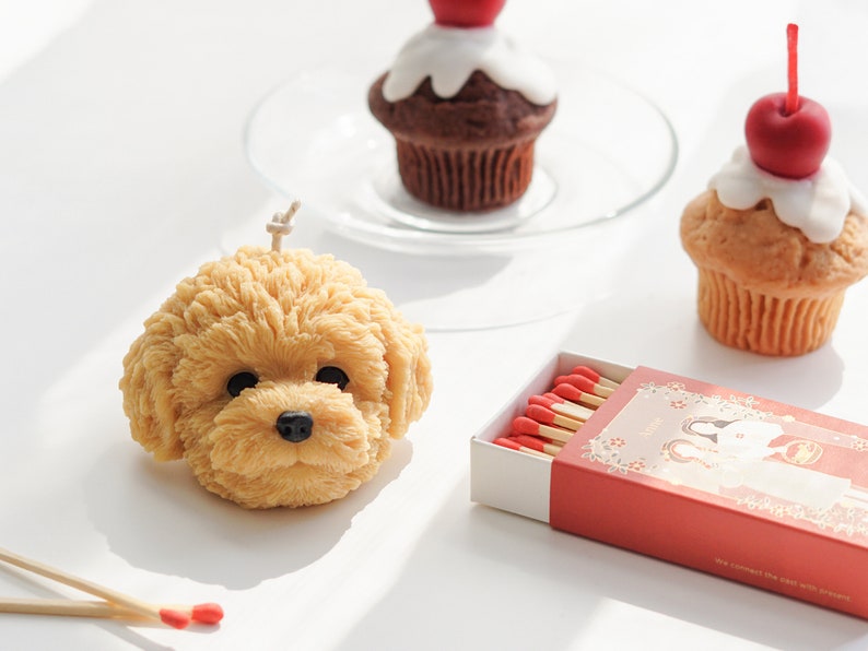 goldendoodle soy pillar candle, cherry muffin candle, chocolate cherry muffin candle on a glass plate, and matches on white table