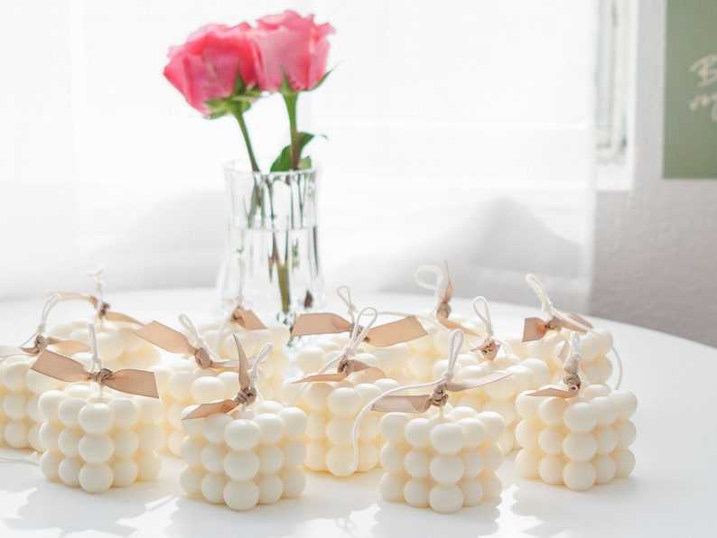 bright sunlight on the desk with lots of aesthetic dreamy minimal style handmade soy wax cube bubble candles and two pink roses in the vase.