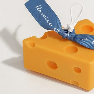 a slice of yellow cheddar cheese shape soy pillar candle with a blue bluewine studio ribbon