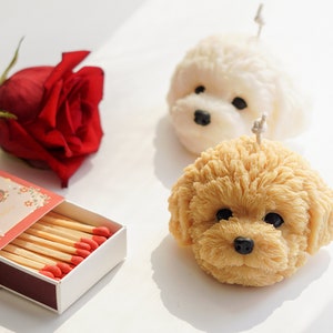 There are two handmade soy wax dog shaped candle, one flower which is rose and cute matches on the desk.