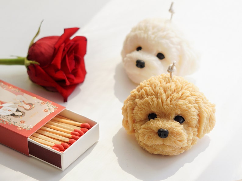 There are two handmade soy wax dog shaped candle, one flower which is rose and cute matches on the desk.