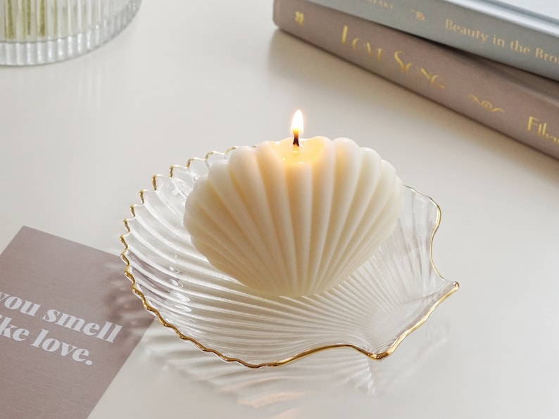 a neutral tone grey tone down colors of aesthetic books, you smell like love text post card, clear transparent and gold finished detail textured seashell candle holder or jewelry dish tray with white minimal seashell candle with beige ribbon on top.