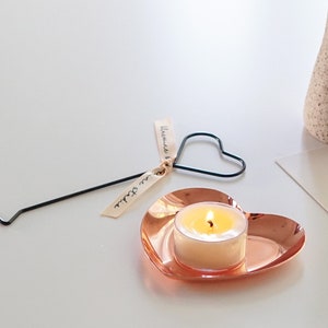 a lit tealight candle on rose gold heart shape tray with heart candle wick dipper