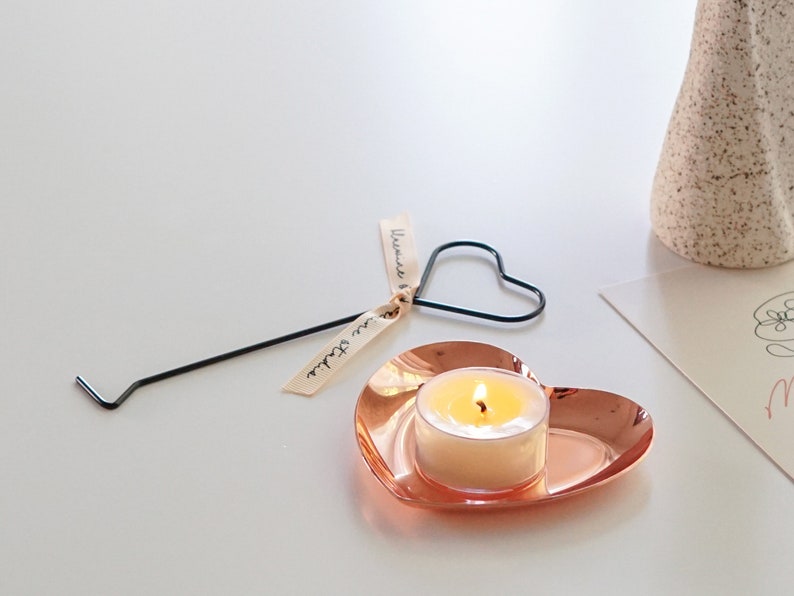 a lit tealight candle on rose gold heart shape tray with heart candle wick dipper