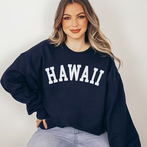 May include: A navy blue sweatshirt with the word "HAWAII" printed in white on the front.