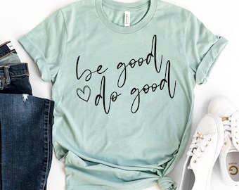 Op de afbeelding: Een lichtblauw t-shirt met de tekst "be good do good" in zwarte schrijfletters met een klein hartje.