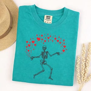 May include: A handmade wooden sign with the text "Welcome" in a handwritten style. The sign is painted white with a distressed finish and features a decorative floral design in shades of pink and green. It is designed for indoor or outdoor use.