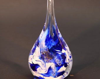 May include: A blue and white glass teardrop-shaped ornament with gold flecks and air bubbles.