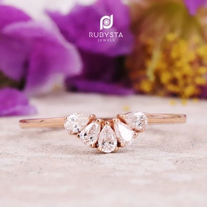 May include: A rose gold ring with a curved band and five pear-shaped diamonds set in a graduated pattern.