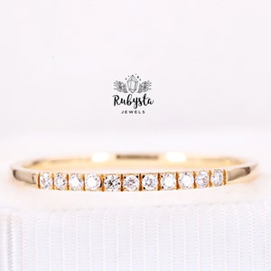 Op de afbeelding: Een delicate gouden ring met een rij kleine, heldere diamanten in een rechte lijn.