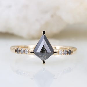 May include: A gold engagement ring with a black diamond center stone and a band of smaller diamonds.