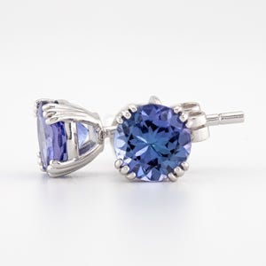 May include: A pair of silver stud earrings with round, faceted, blue gemstones.