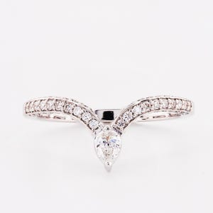 Peut inclure: Une bague en diamant de forme poire avec une bande en V sertie de diamants plus petits.