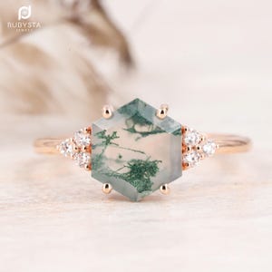 May include: A hexagonal green moss agate engagement ring with a rose gold band and small diamonds on the sides.