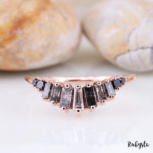 Peut inclure: Une bague en or rose avec une rangée incurvée de diamants noirs taille baguette et un seul diamant blanc au centre.
