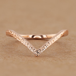 May include: A rose gold hammered V-shaped ring.
