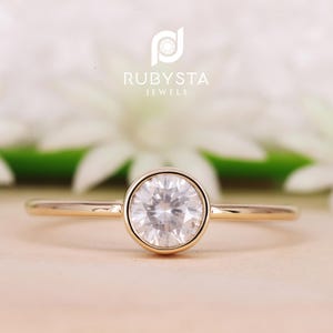Peut inclure: Une bague simple en or avec un diamant rond solitaire serti clos.